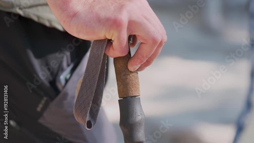 Close-up of a hiker's hand gripping the handle of a trekking pole during an outdoor adventure, highlighting hiking gear, endurance, and stability on the trail.