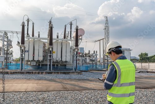 Schilderij op canvas Engineer recording inspection data at power transformer yard in electrical substation, documenting equipment status and asset condition to support preventive maintenance and grid stability