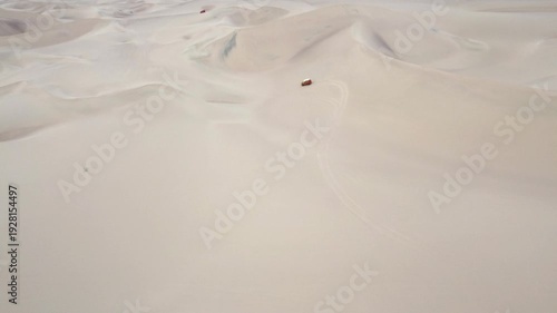 Aerial view drone Dune Buggy car on sand Extraordinary dessert right behind the Oasis city in Huacachina, Ica, Peru cloudy day 4k.
