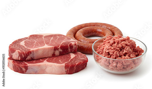 Assortment of fresh raw meat: two ribeye steaks, ground beef in a glass bowl, and a spiral sausage. High-quality butcher products isolated on a white background for food industry use.