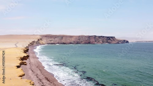 Drone aerial view, red sand beach, big waves and road in desert cliff blue sea clear sky blue. Paracas National Park, Peru 4k