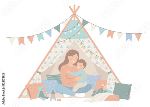 Loving mother and her happy son sitting together and hugging inside a cozy teepee tent decorated with garlands, lights, and pillows for playtime