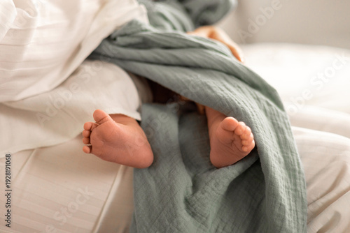 Mother feeding newborn baby with milk bottle at home. Warm parenting moment showing maternal care, bonding and infant nutrition in a calm family environment.