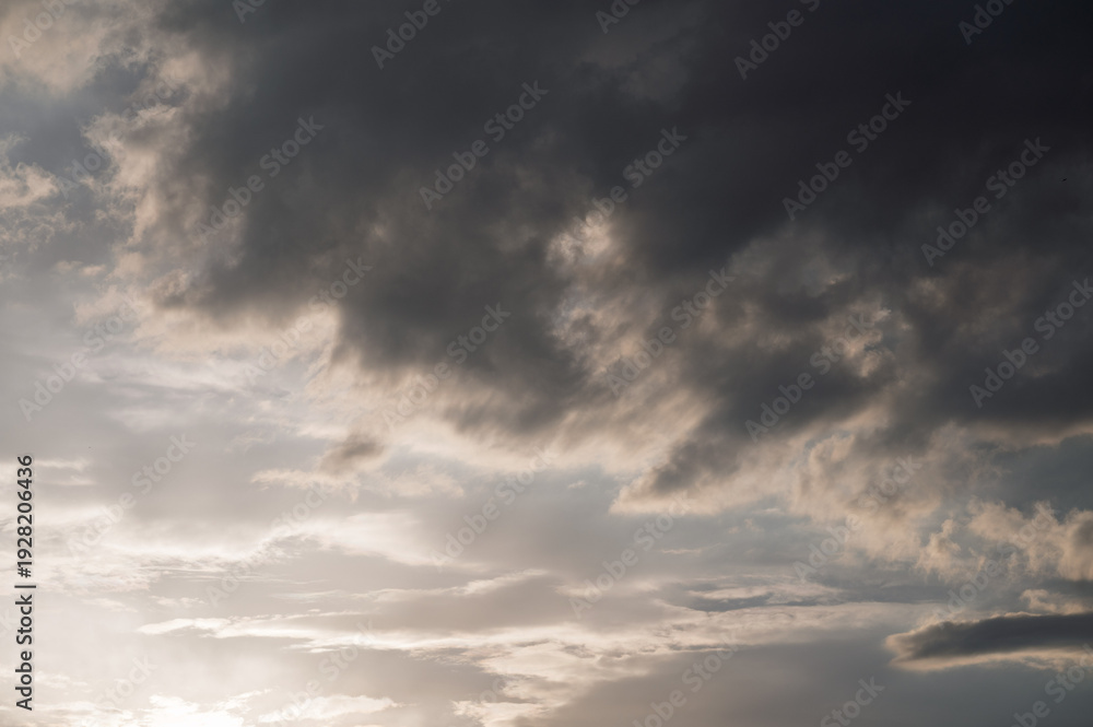 Fototapeta premium Dramatic sunset sky with dark storm clouds and soft light, moody atmosphere before rainfall