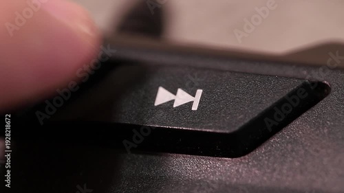 Skipping to the next song or video on a computer keyboard, macro shot of human finger clicking forward button