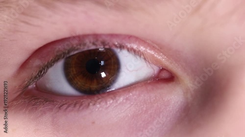 Extreme macro close-up of a young boy's brown eye looking directly at the camera and blinking.