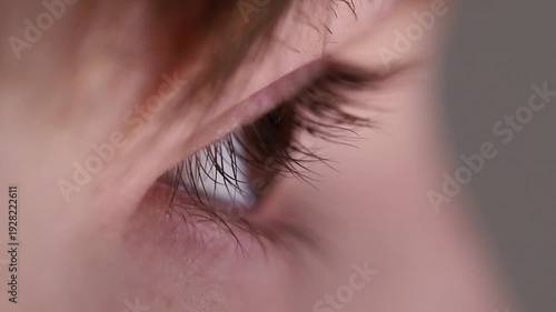 Extreme macro side view of a young boy's eye and long eyelashes as he blinks.