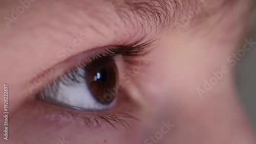 Extreme macro side view of a young boy's eye and long eyelashes as he blinks.