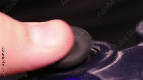 Macro shot of a child's thumb controlling a grimy analog joystick on a game controller.
