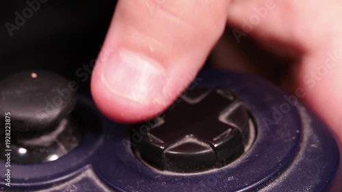 Pressing directional buttons on a neglected old game controller, macro shot of a boy playing video games.