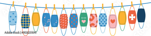 Row of colorful reusable fabric face masks with various patterns and designs hanging on a blue clothesline with wooden pins isolated on white background