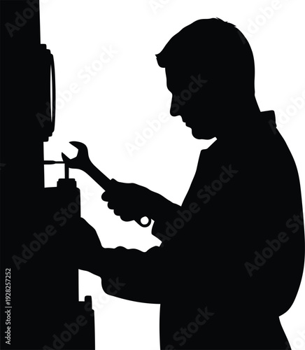 Silhouette of male mechanic using wrench for machine repair in industrial workshop