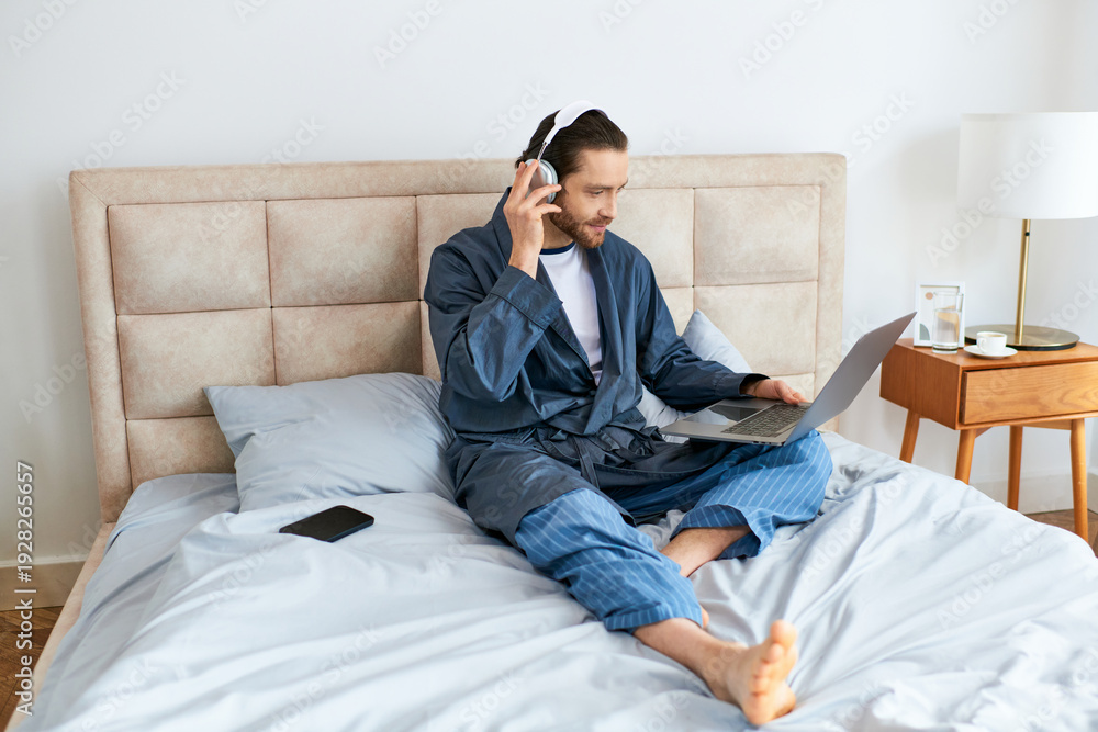 Fototapeta premium Relaxed man enjoys a cozy moment at home while working on his laptop in comfortable attire