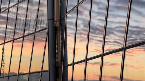 Canvas Print Close-up of modern skyscraper glass facade reflecting pink and orange sunset clo