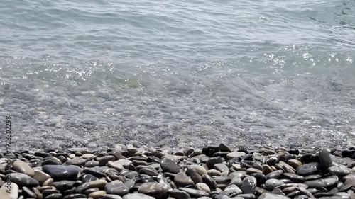 Waves splash on stones at the beach near water