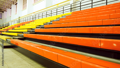 Fotografía Rows of empty colorful orange and yellow stadium seats in Indoor sports arena bleachers or grandstand background for spectators
