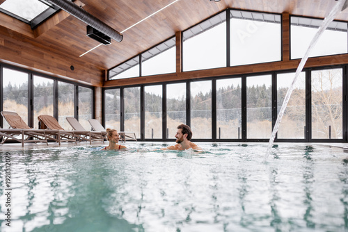 Konstfotografi Happy couple relaxing and having fun in a modern indoor swimming pool during win