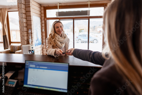 Obraz na plátně Woman guest checking in at hotel reception desk, receiving room key card