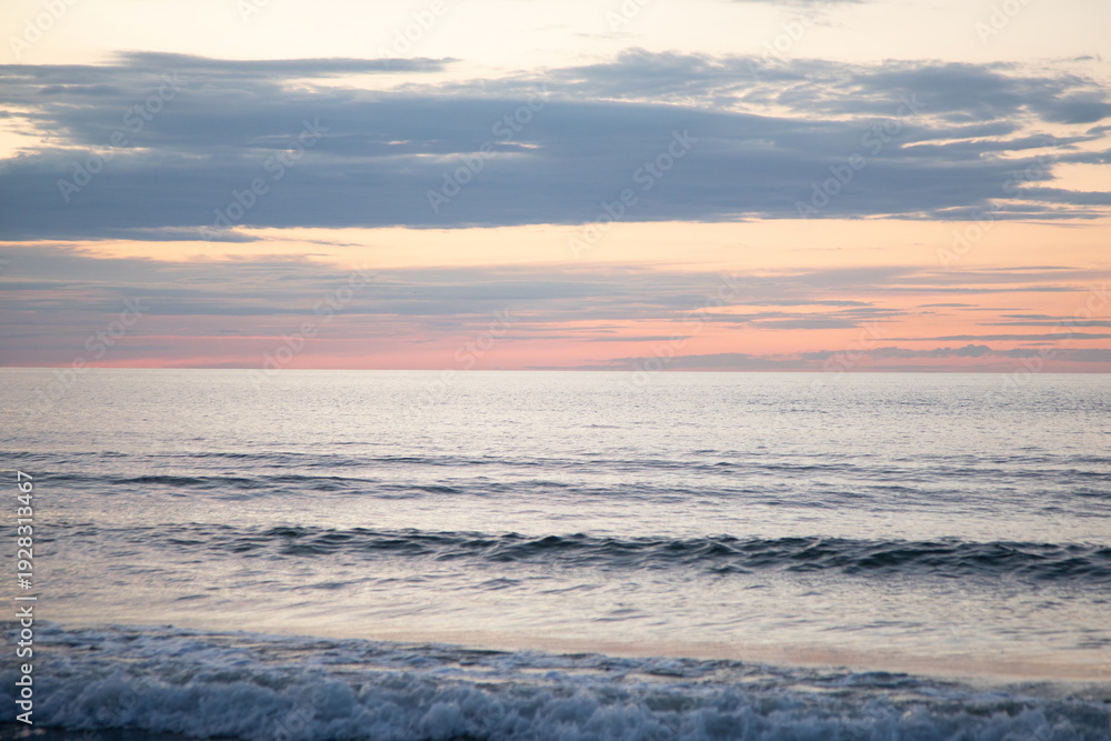 Fototapeta premium Dreamy beach sunset with soft waves and warm evening glow