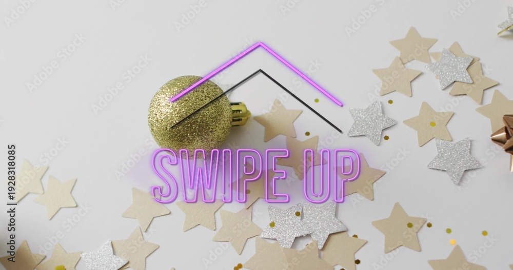 Fototapeta premium Displaying centered purple neon SWIPE UP text overlay glowing on light tabletop, with gold bauble