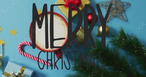 Resting red mug holding hot cocoa on blue tabletop, with candy cane, gift, MERRY CHRISTMAS text