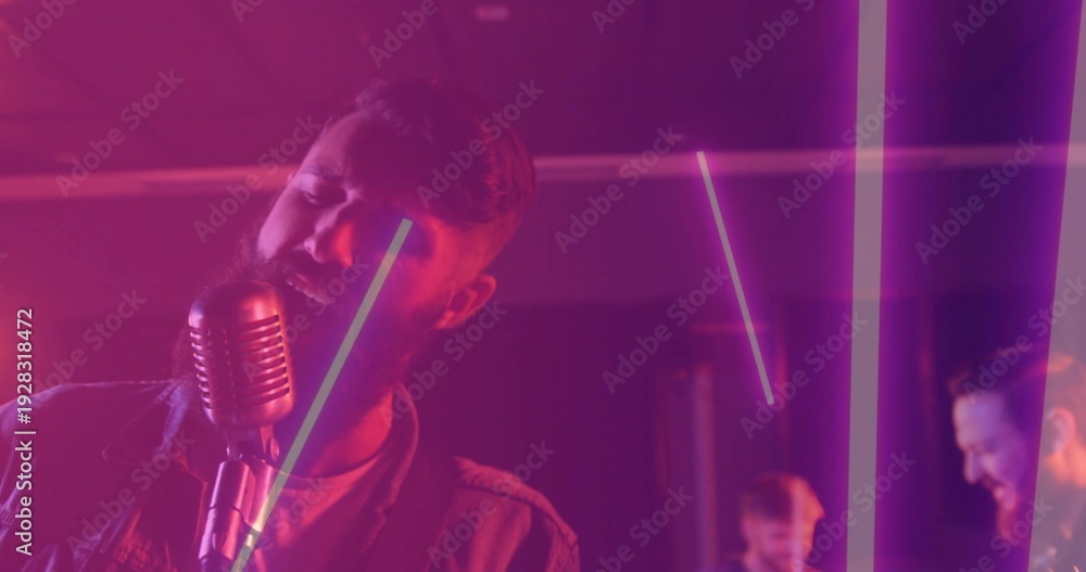 Obraz premium Singing singer in casual jacket leaning toward vintage mic stand on stage with LED tubes, amps
