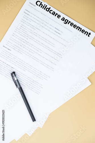 Childcare agreement contract on desk, legal document about child care services, parental responsibilities, and family support concept.