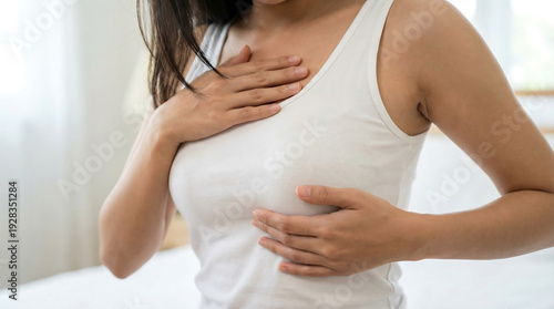 Wallpaper Mural Young woman performing a breast self examination for cancer prevention while sitting on her bed at home Torontodigital.ca