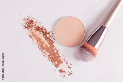 Compact face powder with makeup brush on white background