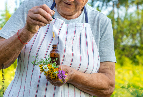 Obraz na plátně Old woman makes herbal tincture. Selective focus.