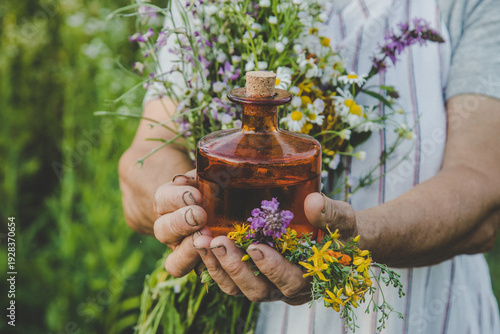 Fotografie Old woman makes herbal tincture. Selective focus.