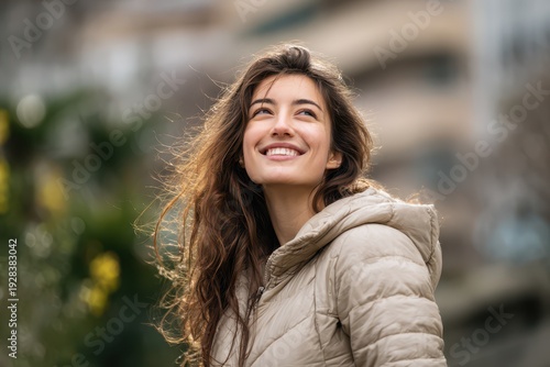 Portrait of a young woman in a warm down jacket smiling and looking upward