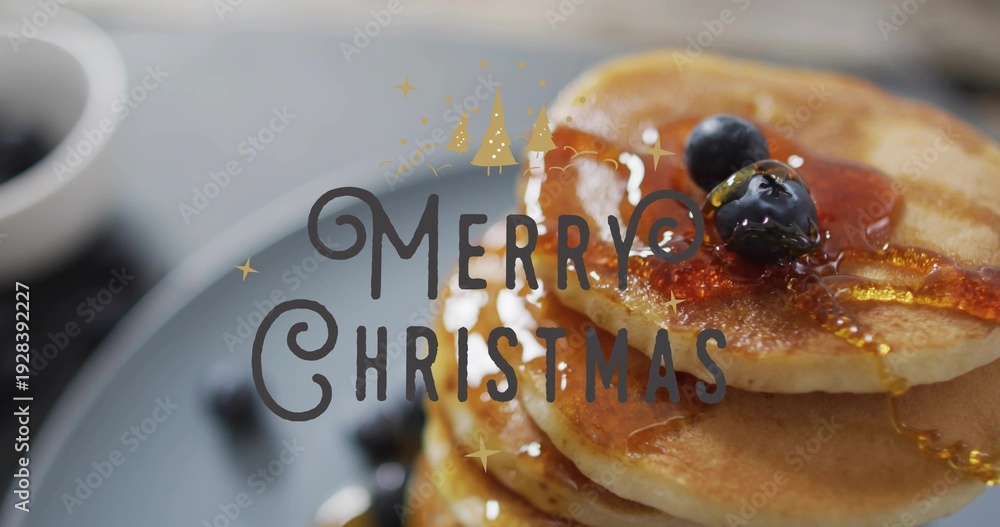 Obraz premium Showing pancake stack shining on tabletop with blueberries, maple syrup, Merry Christmas overlay