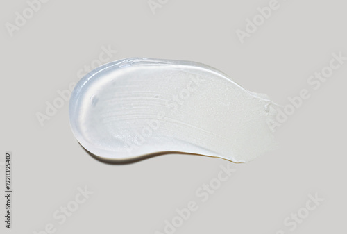 Cosmetic gel emulsion or serum vaseline mask with luminizer effect brush stroke smudge isolated on neutral grey background