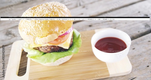 Sesame burger sitting on cutting board on rustic plank table, with ketchup bowl, cheese, code lines