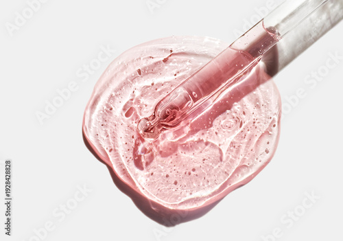 Liquid pink red orange oil or serum on neutral gray isolated background. Beauty product sample swatch