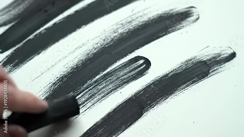 Black brush strokes applied diagonally to a white surface with a textured appearance