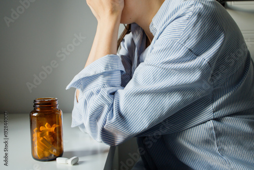 Tableau sur toile Sad depressed woman taking antidepressants pills from small brown glass bottle