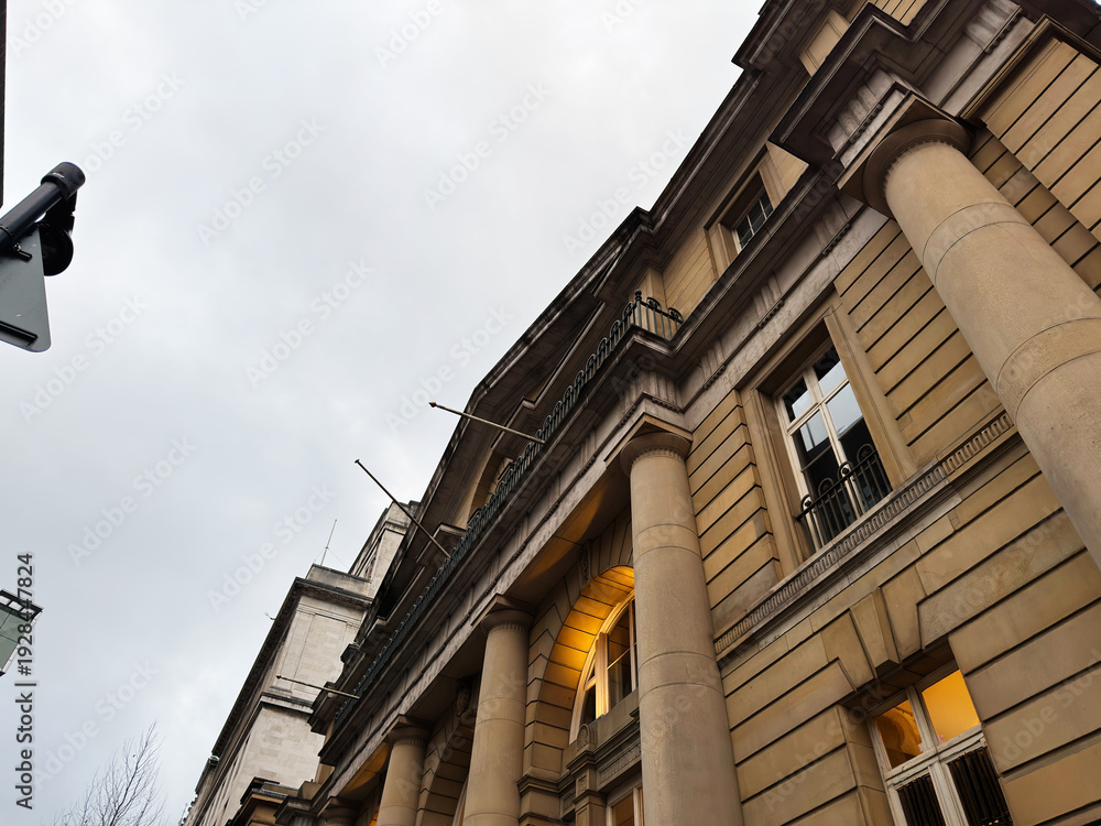 Naklejka premium Manchester town hall style building with columns and warm light under cloudy sky neoclassical facade