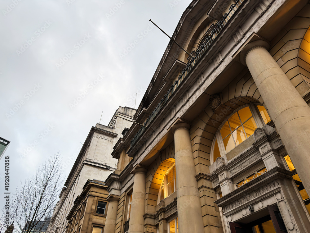 Fototapeta premium Historic Manchester building with grand columns and warm illuminated arches at dusk UK
