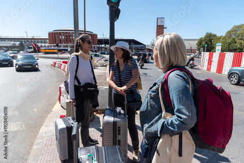 Women travelers waiting for ride with suitcases in madrid