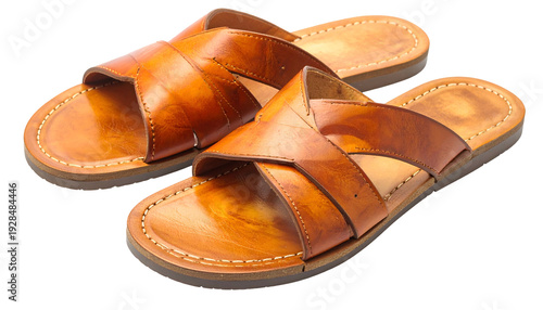 Close-up studio shot of two brown leather sandals with criss-cross straps, sitting on a transparent background