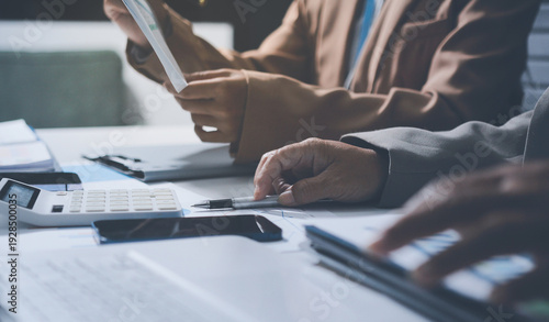 Business colleagues analyzing financial charts and reports on the table while having a focused discussion about strategies and market performance during an important meeting in a modern office setup