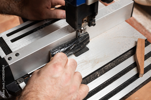 A craftsman saws off a piece of horn to make a nut for a string instrument