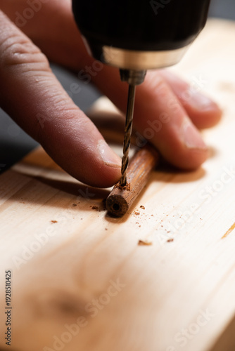 The craftsman drills a hole in a wooden part
