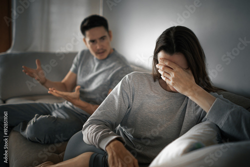 man arguing while woman covers face on couch, unhappy couple and relationship conflict at home
