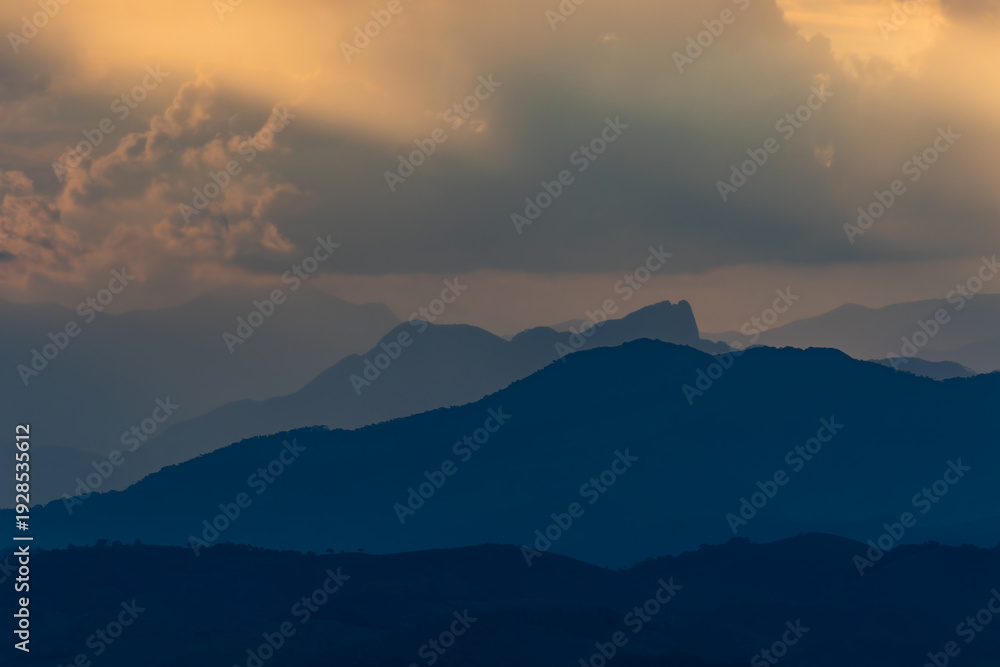 Obraz premium Sunset Light Casting Over Layered Mountain Peaks