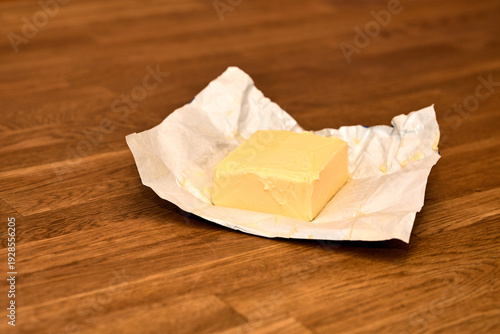 Block of Fresh Butter in Wrapper on Wooden Table