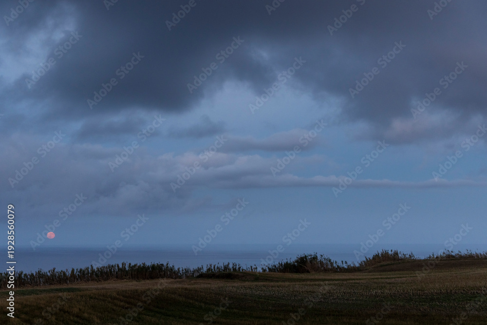 Fototapeta premium A cloudy sky with a bright red moon in the background