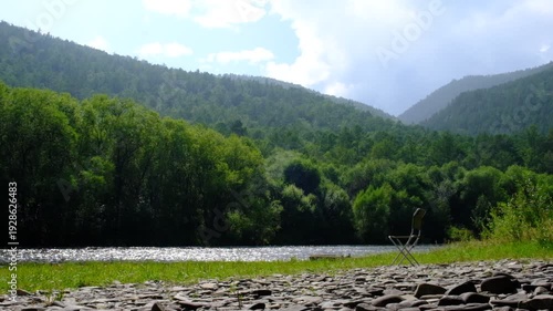 Camping chair next mountain river. An ideal place to watch beauty in nature. Active relaxing lifestyle, vacations, adventure, bushcraft